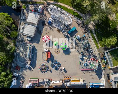 Blick von oben auf eine lebhafte Vergnügungspark-Anlage am City Park Ice Rink & Bootstouren in Budapest, umgeben von Grün und Wasser, Stockfoto