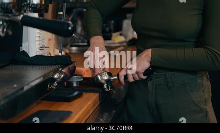 Nicht wiedererkennbare kaukasische Kellnerin, die Energie-Drink macht Barkeeper-Mädchen hat gemahlenen Kaffee-Klopfkastenangestellten-Catering-Job in der Cafeteria Stockfoto