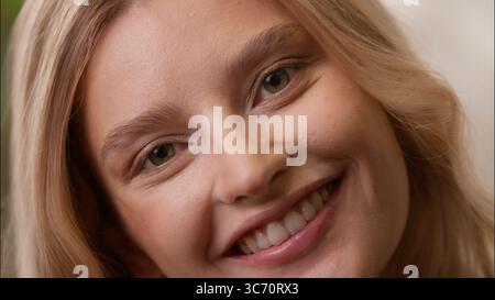 Sorglose positive kaukasische weibliche Gesicht Nahaufnahme posierende erwachsene Dame lächelnd mit gesunden weißen Zähnen Schönheit Zahnheilkunde zu Hause blonde Frau Mädchen schauen Stockfoto