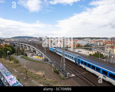 Zug der České dráhy (Tschechische Eisenbahnen) auf der Bahnstrecke in Prag. Großes Brückengebäude in der Hauptstadt. Öffentliche Verkehrsmittel in Tschechien. Stockfoto