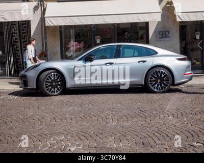 Cremona, Italien 28. Juli 2025 der moderne silberne Porsche Panamera parkt auf einer europäischen Kopfsteinpflasterstraße vor einer Luxusboutique, die einen Gli anbietet Stockfoto