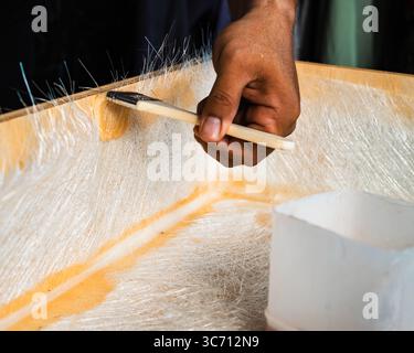 Bürsten Sie Glasfaserplatten auf einer Holzkiste. Ein heimwerkerprojekt zu Hause. Stockfoto