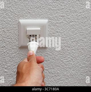 Elektrokabel mit der Hand in den schweizer Netzstecker stecken. Stockfoto