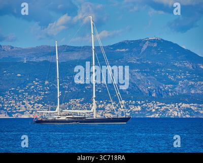 Luxuriöse Segelyacht Drumbeat in Anchor in der Nähe der malerischen Küste mit bergiger Kulisse Stockfoto
