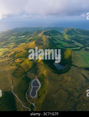 Blick aus der Vogelperspektive auf Zwillingsseen, eingebettet in grüne Hügel, ein Wandteppich aus Licht und Schatten, der die Landschaft in Kontrasttönen malte, Sete Cidades, Portugal. Stockfoto