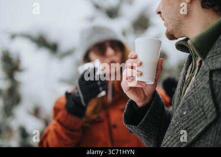 Zwei Erwachsene genießen warme Getränke im Freien in einer winterlichen Landschaft Stockfoto