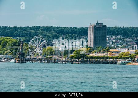 Pulsierender Sommerblick auf den Hafen in Konstanz mit der berühmten Imperia-Statue, dem Riesenrad, dem Yachthafen mit Segelbooten und der Skyline der Stadt Stockfoto