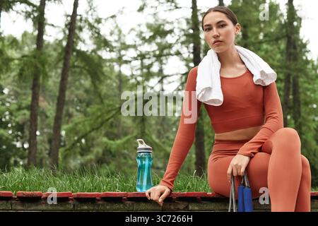 Die schöne junge Frau genießt einen Moment der Ruhe in der Natur, nachdem sie einen Yoga-Kurs unterrichtet hat. Stockfoto