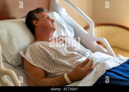 Patient, der eine Schwester mit Fernbedienung im Krankenhausbett ruft. Stockfoto