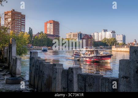 Die Touristen, die mit dem Boot auf dem Fluss Pregolya in Kaliningrad fahren, umgeben von Stadtarchitektur im Westen Russlands. Stockfoto
