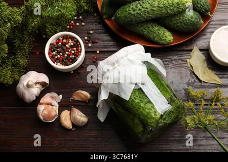 Eingelegte Gurken im Gefäß, frische Gurken, Knoblauch, Dill und Gewürze auf Holztisch, flach gelegt Stockfoto