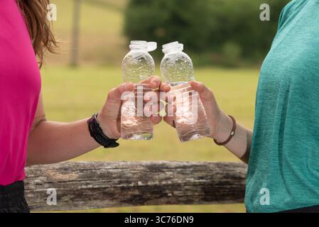 Frauen, die mit Wasser tosten, nachdem sie in einem Park gelaufen sind Stockfoto