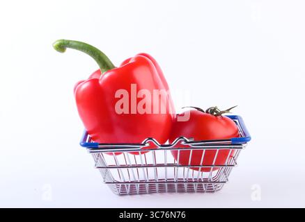 Mini-Einkaufskorb mit roter Paprika und Tomate auf weißem Hintergrund. Supermarktkonzept Stockfoto