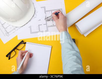 Arbeitsbereich „Engineering“. Weibliche Hände führen Berechnungen und Messungen auf gelbem Hintergrund durch. Draufsicht Stockfoto