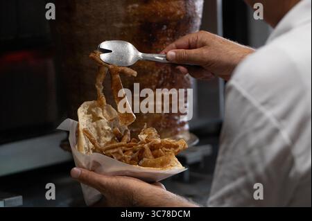 Stuttgart, Deutschland. August 2025. Ein Mann füllt ein Fladenbrot mit Fleisch aus einem Dönerspieß. Der Spieß wurde von der Firma Birtat hergestellt. Quelle: Markus Lenhardt/dpa/Alamy Live News Stockfoto