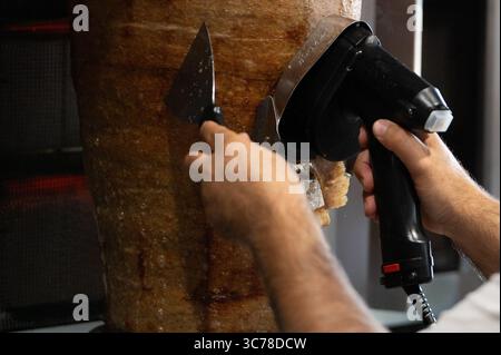 Stuttgart, Deutschland. August 2025. Ein Mann schneidet Fleisch von einem Dönerspieß, der von der Firma Birtat hergestellt wurde. Quelle: Markus Lenhardt/dpa/Alamy Live News Stockfoto