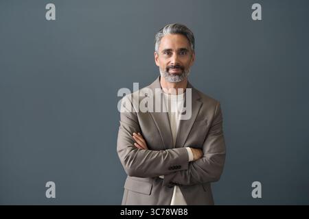 Glücklicher Geschäftsmann mittleren Alters, der auf grauen Hintergrund in die Kamera blickt. Stockfoto