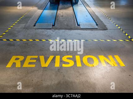 Hydraulikanlage für Hebebühne für Fahrzeuginspektion im italienischen Autoverkehr mit gelbem Schild: Revisione (Inspektion). Rechtliche Kontrollen der Fahrzeugeffizienz Stockfoto