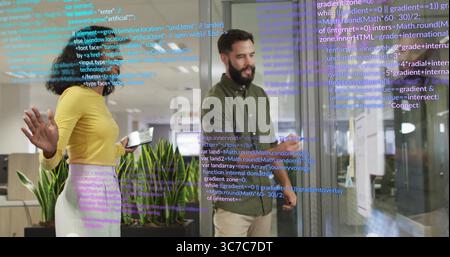 Zwei Software-Ingenieure analysieren Code an Glaswänden im Büro mithilfe von Tablet-Eingabestiften und Monitoren Stockfoto