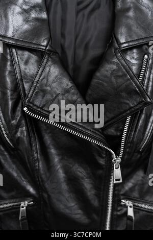 Nahaufnahme einer schwarz glänzenden Bikerjacke aus Kunstleder mit silbernen Reißverschlüssen und Druckknopfkragen Stockfoto