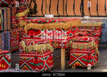 Ein Tisch und passende Hocker, dekoriert mit traditionellen geometrischen roten und schwarzen anatolischen Kelims in einer Straße in einem Café in Istanbul, Türkei Stockfoto