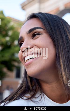 Junge lateinfrau lächelt im Freien in urbaner Umgebung Stockfoto