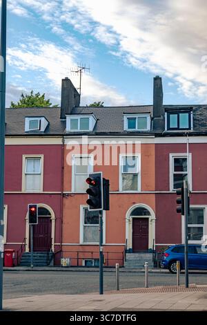 25. Juli 2025 Cork, Irland Ein blauer Wagen steht vor einer langen Reihe verschiedener Häuser Stockfoto