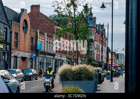 25. Juli 2025 Cork, Irland Eine fesselnde und lebhafte Urban Street Scene mit einer Vielzahl von Geschäften und üppigem Grün Stockfoto