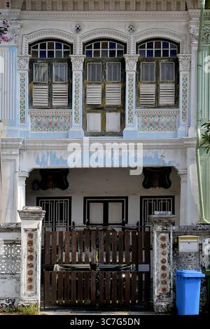 Äußere eines traditionellen Peranakan-Terrassenhauses der Straße mit verblasstem Anstrich, verziertem Rokoko-Putz und floralen Mosaikfliesen Stockfoto