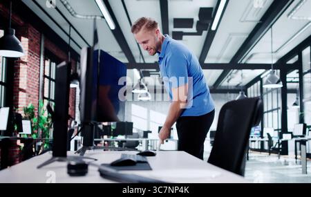 Lächelnder Hausmeister Im Blauen Overall Wischt Den Büroboden Für Die Arbeit. Stockfoto