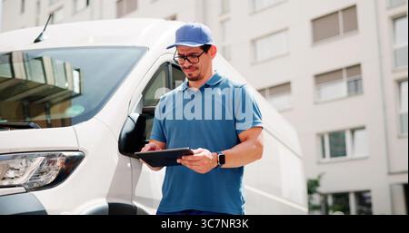 Liefermann Mit Tablet In Der Nähe Eines Trucks, Glücklicher Kurier In Uniform Stockfoto