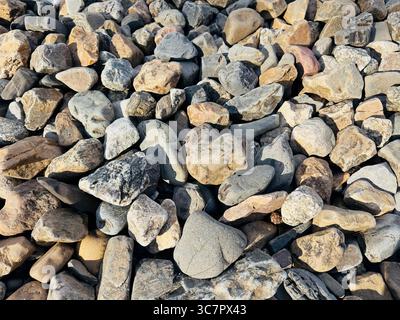 Eine lebendige Sammlung von glatten Flussfelsen zeigt verschiedene Formen und Farben. Stockfoto