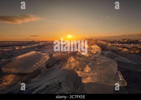 Der Sonnenuntergang spiegelt sich in einem großen Block Eishummock auf dem gefrorenen Seegrund wider. Stockfoto