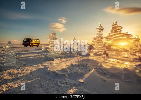 Der Sonnenuntergang spiegelt sich in einem großen Block Eisbuckel und einem klassischen Oldtimer auf dem gefrorenen See. Stockfoto