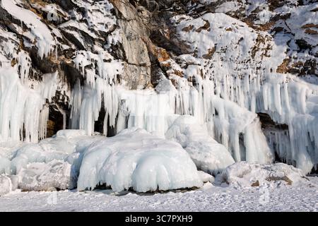 Baikalsee am kalten Wintertag. Schöne Eisfelsen mit großer Eiskruste. Lange Eiszapfen an den eisigen Küstenklippen von Olkhon Island Stockfoto