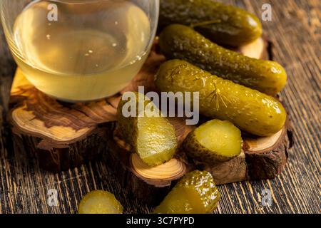 Eingelegte Gurken und eingelegte Reifen Gurken neben einem Glas, gegossene Gurken mit Gewürzen und ganze knusprige Gurken auf ein Brett Stockfoto