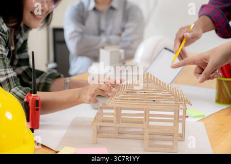 Eine Gruppe von Architekten untersucht ein Gebäudemodell und diskutiert moderne Design- und Konstruktionstechnologie in einem kollaborativen Arbeitsbereich. Stockfoto