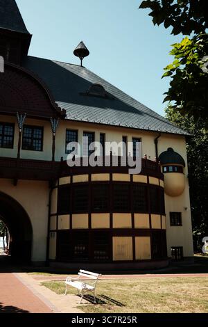 Abgerundete Ecke und kuppelförmige Details in einem historischen Gebäude in Palic, Serbien, mit einer weißen Bank davor. Stockfoto