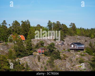 Traditionelle schwedische Ferienhütten auf Inseln von einem Kreuzfahrtschiff aus gesehen. Diese kleinen Häuser werden als Wochenendrückzugsorte und Ferienhäuser genutzt. Stockfoto