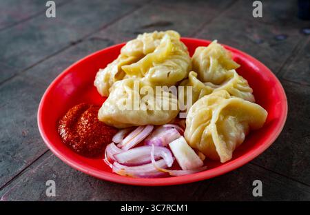 Hot Momos serviert mit scharfem Red Chutney an einem Straßenstand in Dehradun, Indien Stockfoto