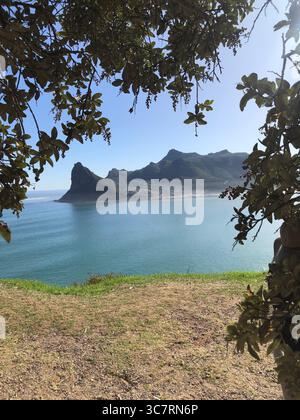 Atemberaubende Küstenlandschaft von Hout Bay, Südafrika, mit friedlichem Hafen und dramatischer Bergkulisse. Stockfoto