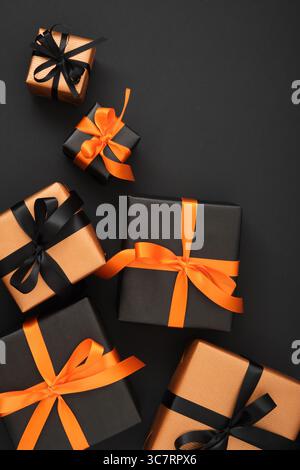 Schwarz-orange Geschenkboxen mit Bändern auf schwarzem Hintergrund. Platz für Ihren Text. Stockfoto