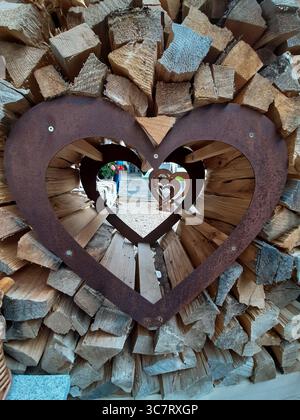 Ein dekoratives Metallherz in einem Holzhaufen Stockfoto