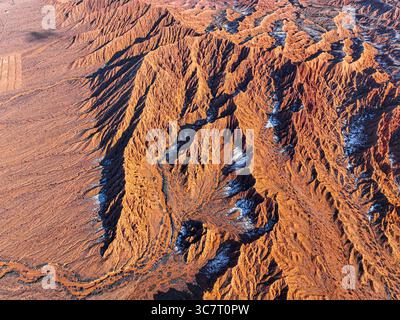 Eine hochwinklige Drohnenaufnahme fängt die komplizierte, erodierte rote Felsenlandschaft des Mars Canyon mit kleinen Schneefällen ein Stockfoto