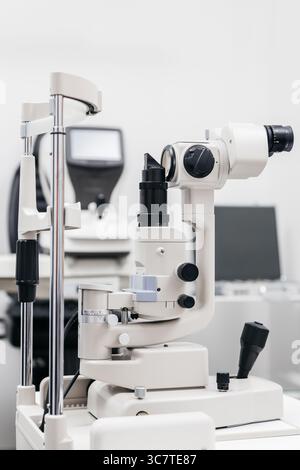 Spaltlampe für die Augenheilkunde, positioniert in einer hellen klinischen Umgebung, die Präzisionsinstrumente für gründliche Sehtests und Augenaugenwagen hervorhebt Stockfoto