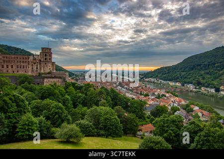 Blick von einem Hügel über eine Altstadt mit Burgruinen. Landschaftsaufnahme bei Sonnenuntergang in Heidelberg Stockfoto