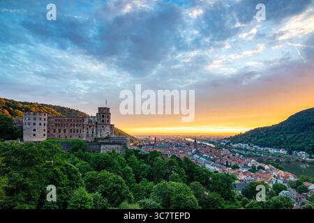 Blick von einem Hügel über eine Altstadt mit Burgruinen. Landschaftsaufnahme bei Sonnenuntergang in Heidelberg Stockfoto