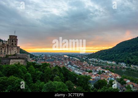 Blick von einem Hügel über eine Altstadt mit Burgruinen. Landschaftsaufnahme bei Sonnenuntergang in Heidelberg Stockfoto