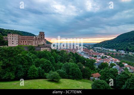 Blick von einem Hügel über eine Altstadt mit Burgruinen. Landschaftsaufnahme bei Sonnenuntergang in Heidelberg Stockfoto