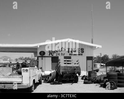 Schwarz-weiß-Ansicht des Autoherstellers von Revert mit gestapelten Reifen und Werkzeugen am Straßenrand. USA West, August 2007. Eine düstere Americana-Szene. Stockfoto
